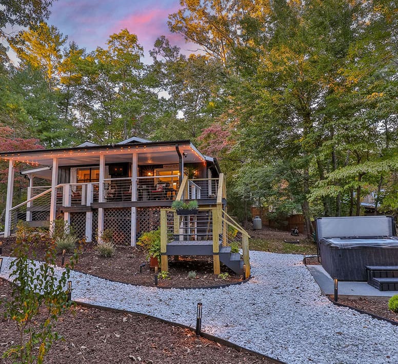 A cabin with a hot tub and a large deck.