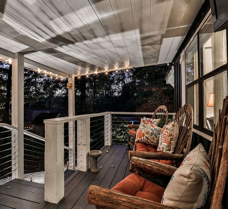 A porch with chairs and lights on the ceiling.