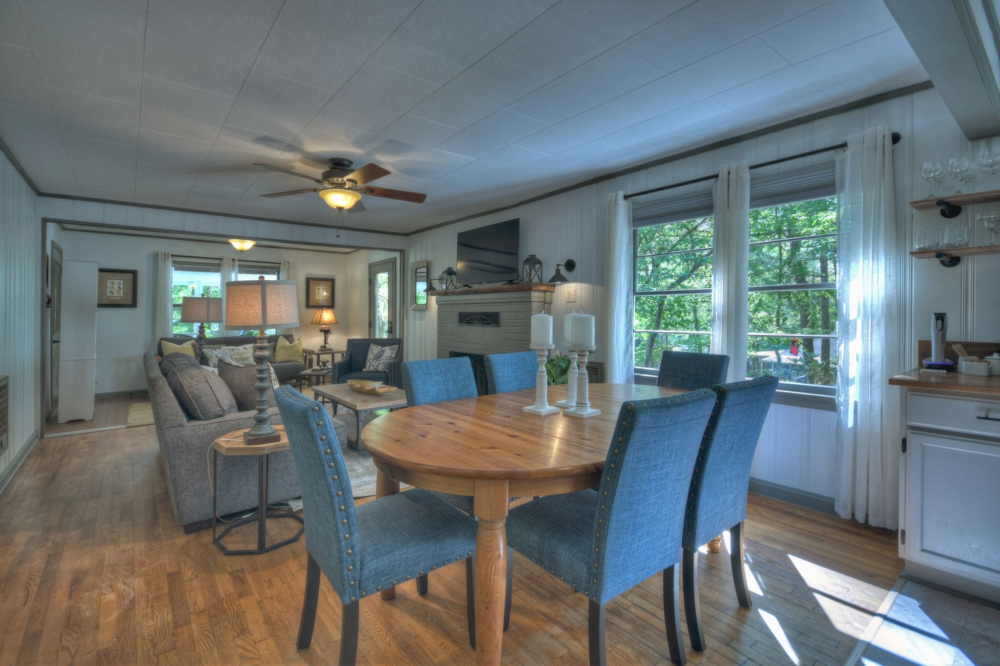 A dining room table with blue chairs and a couch in the background.