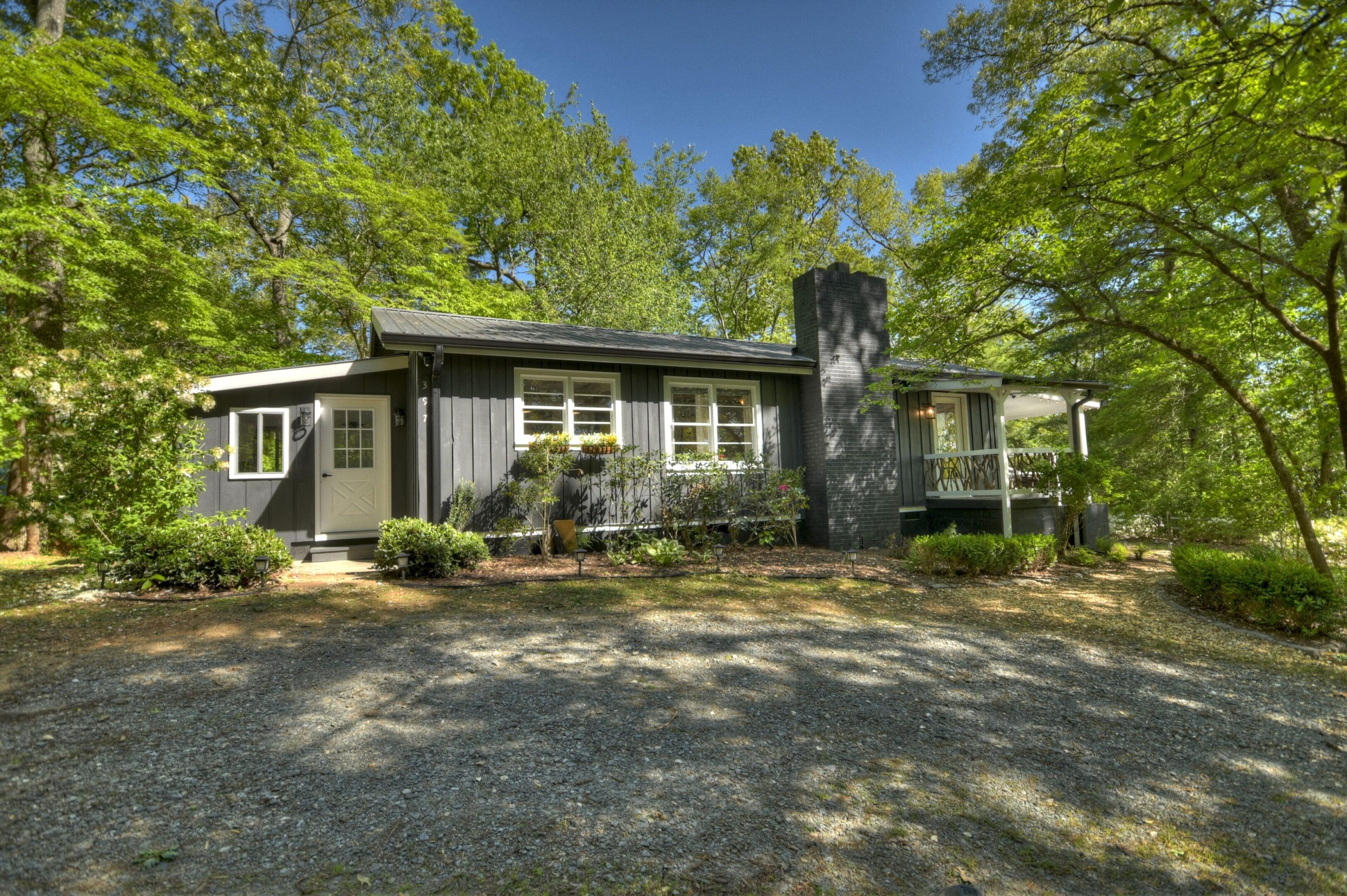 A house with trees in the background and a driveway.